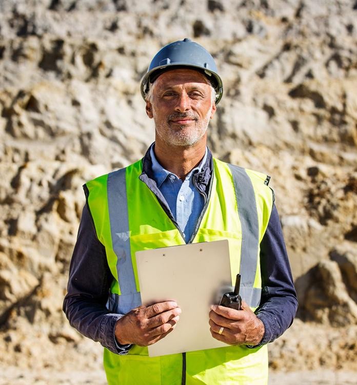 Man wearing hi-vis standing next to heavy machinery